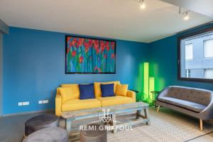 a living room with blue walls and a yellow couch at The Cosmopolitan Architect Design Home with Rooftop Jacuzzi 8 Guests in Honfleur