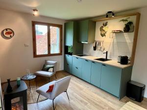 a kitchen with blue cabinets and a table and a window at Le Charme du Perigord - chambre & table d'hotes in Saint-Sulpice-dʼExcideuil