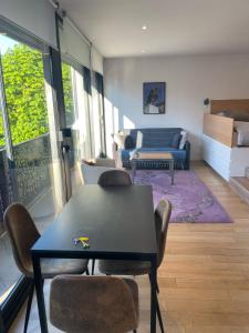 a living room with a table and chairs and a couch at Studio moderne à 15mn de la Défense in La Garenne-Colombes