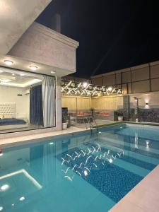 Al RamaFiruza Farm Villa Vip的夜晚的大型游泳池，旁边有一面大镜子。