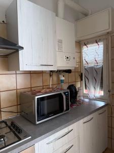 a kitchen with white cabinets and a microwave on the counter at Alassio Family Apartment - Balcone, Cucina, WiFi e Garage in Alassio
