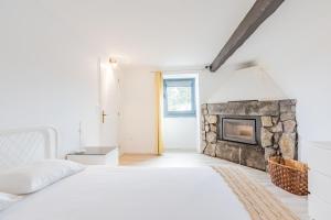 a white bedroom with a fireplace and a bed at Solar do Maranhão in Capelas