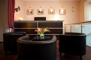 a bar with black chairs and a table with a vase of flowers at Station Aparthotel in Kraków