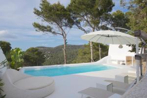 a swimming pool with an umbrella and chairs and a swimming pool at JAMES SIB19 - luxury Cala Vadella villa with pool and stunning sea view in Sant Josep de Sa Talaia