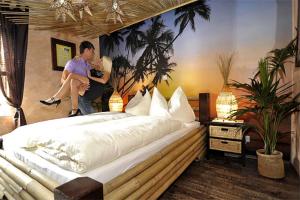mężczyzna i kobieta siedzący na łóżku w obiekcie "Das Schlafzimmer" Erlebnis & Boutiquehotel - ehemals Hacienda Mexicana w mieście Spittal an der Drau