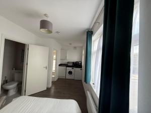 a room with a bed and a bathroom with a kitchen at Comfy family studio in Goodmayes