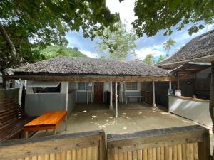 a building with a thatched roof with a bench at Rosies Beach House El Nido in El Nido