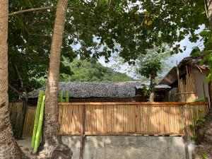 a wooden fence next to a tree and a house at Rosies Beach House El Nido in El Nido
