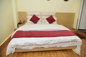 a bedroom with a large bed with red pillows at Bhoomi Palace Hotel 2 O and Bella's Bites Restaurant in Gorakhpur