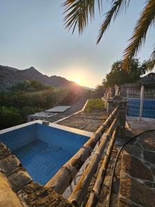 a swimming pool with the sunset in the background at Alnessayem Farmhouse in Sayḩ aş Şaqlah