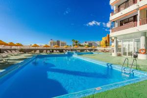 una grande piscina blu accanto a un edificio di Apartamentos Olympia a Playa de las Americas