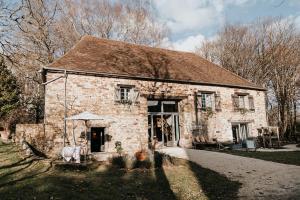 an old stone house with two chairs in front of it at La Petite Grange des Vignes in Jumilhac-le-Grand