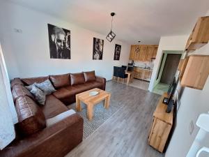 a living room with a brown couch and a table at Apartman Lilly in Modriča