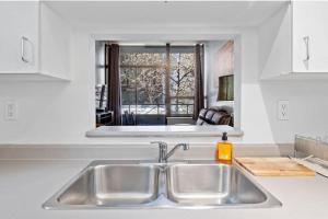 - un lavabo dans la cuisine avec un miroir au-dessus dans l'établissement Cozy 1 Bedroom Downtown Central, à Vancouver 12 autres photos