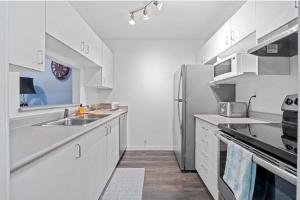 une cuisine avec des armoires blanches et un réfrigérateur en acier inoxydable dans l'établissement Cozy 1 Bedroom Downtown Central, à Vancouver