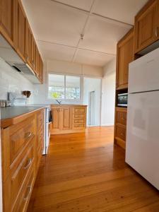 a kitchen with wooden cabinets and a white refrigerator at Sailors Snug in Kelso