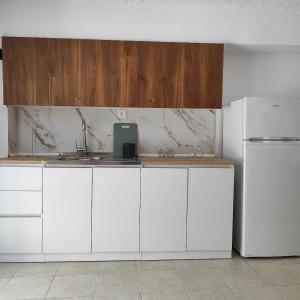 a kitchen with white cabinets and a sink and a refrigerator at Zenith Apt #2 in Pefkohori