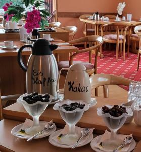 a tea kettle and saucers on a table in a restaurant at Hotel garni SEESCHLÖSSCHEN in Kolpinsee