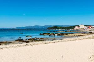 a beach with boats in the water and buildings in the background at Seaside Apartment Sleeps 6 with Balcony in Vilagarcia de Arousa
