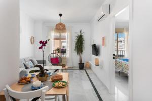 una sala de estar blanca con una mesa con comida. en Casco antiguo terraza y vistas al mar Playa a Pie 1B, en Nerja
