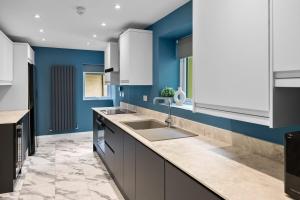 a kitchen with a sink and a blue wall at Stylish 7 Bedroom House in Plymouth +43 photos