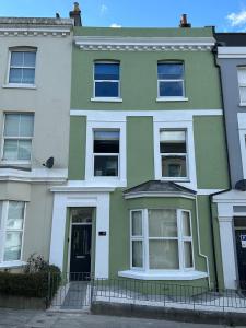 a green and white house with a black door at Stylish 7 Bedroom House in Plymouth