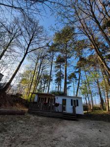 a small white cabin with a porch in the woods at Tiny Sweet Home - 3 nuits minimum in Saint-Chéron