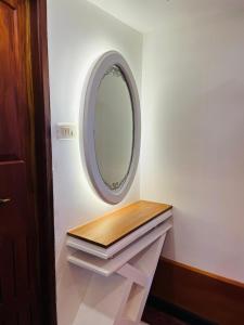 Un baño con espejo y estante de madera. en sajiholidays houseboats, en Alleppey