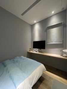 una camera con letto e scrivania con TV di 蘆思特六合民宿 a Kaohsiung