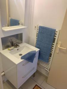 y baño con lavabo, espejo y toallas azules. en Appartement entier en centre-ville avec terrasse, en La Rochelle