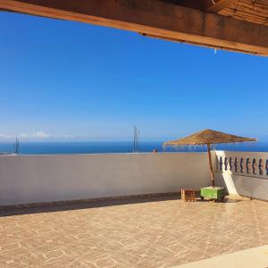 a patio with a chair and an umbrella and the ocean at The View in Taghazout