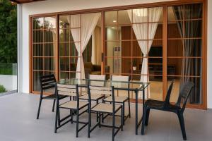 a glass dining table and chairs on a patio at Jachim and Boaz FarmVille Staycation in Tagaytay +17 photos
