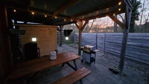 a pavilion with a wooden bench and a grill at Chalet 'Forest Happiness' in Anloo