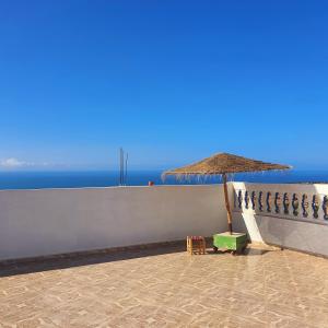 a straw umbrella and a chair next to a wall at The View in Taghazout +18 photos