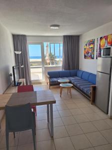 a living room with a blue couch and a table at Apartamento PinkFloyd im Palm Garden in Morro del Jable