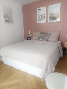 ein großes weißes Bett in einem Schlafzimmer mit zwei Bildern an der Wand in der Unterkunft T5 Hyper center lumineux et cosy in Sceaux
