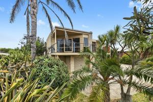 a house with a balcony and palm trees at Miranda Oasis in Torquay