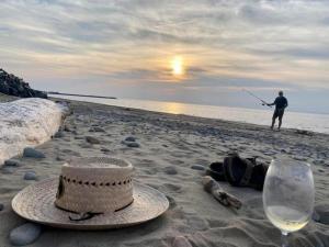 a person fishing on the beach with a hat and a glass of wine at Chez Thomas, la maison du pêcheur in Grande Anse