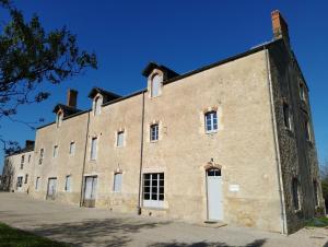 a large brick building with a white door at Chez Marguerite et Bienaimé in Picauville