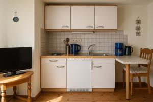 a kitchen with white cabinets and a sink and a tv at Moselglocke Urlaub im Herzen von Zell in Zell an der Mosel