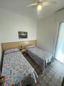 a bedroom with two beds and a ceiling fan at FOSCOLO Sunset House in Lido di Jesolo