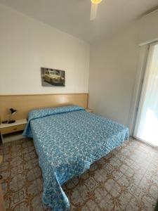 a bedroom with a bed with a blue comforter at FOSCOLO Sunset House in Lido di Jesolo
