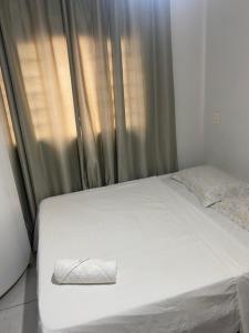 een wit bed met een kussen erop naast een raam bij Dona Angelina in Araçatuba +3 foto's