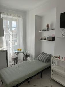 a bed in a room with a table and a window at Cozy studio sur la promenade in Nice
