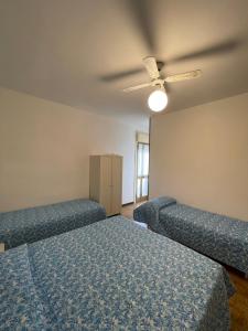 a bedroom with two beds and a ceiling fan at FOSCOLO Sunset House in Lido di Jesolo