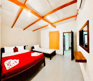 a bedroom with a red bed and a tv at The Wave Rooms & Hostel in Arugam Bay