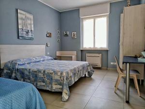 a bedroom with two beds and a desk and a window at Appartamento Mimosa in Boissano