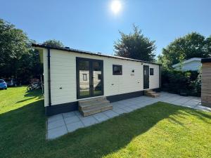 a small white building with a porch on a lawn at Chalet in Makkum - K118 in Makkum