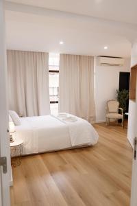 a white bedroom with a large bed and a chair at Apartamento Mira Rio in Celorico de Basto