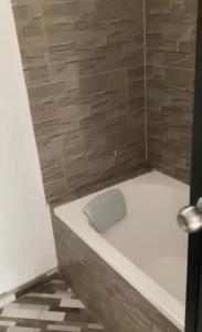 a bathroom with a white bath tub next to a stone wall at El descanso verde in San Carlos
